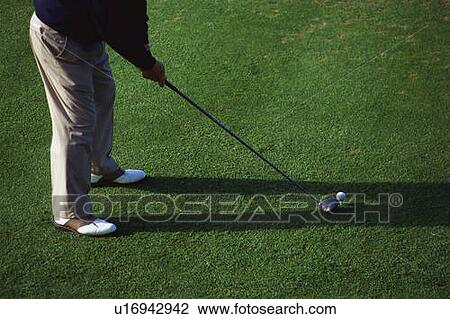 Stock Image - Golfer putting on the green. Fotosearch