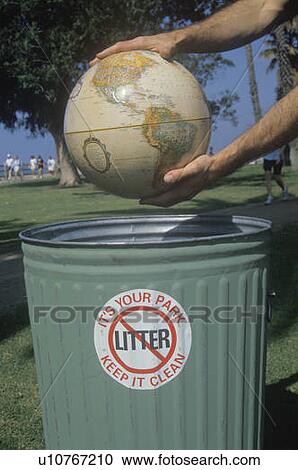 Stock Image - Hands holding a globe over a park trash receptacle . Fotosearch