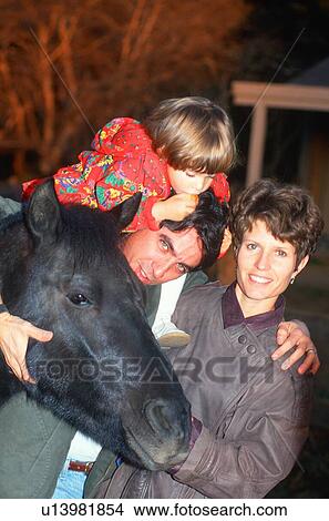 Picture - Little girl on horseback with her parents. Fotosearch