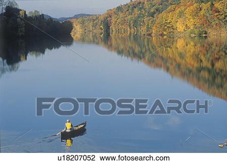 Stock Image - Man canoeing on Connecticut River in autumn. Fotosearch
