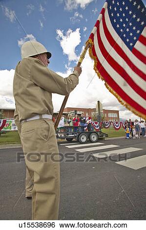 Stock Photograph - Member of a color guard carrying an American flag. Fotosearch