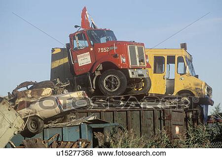 Stock Photo - Old trucks and cars sitting on top of a scrap heap in a junk yard. Fotosearch
