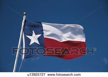 Stock Photo - State Flag flying in the wind. it is on a flagpole against a blue sky. Fotosearch
