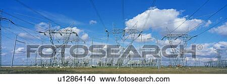 Stock Image - These are electrical utility lines set against a blue sky with white puffy clouds.. Fotosearch
