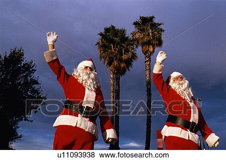These are two people dressed as Santa next to palm trees View Large Photo Image Stock Photo - These are two people dressed as Santa next to palm trees. Fotosearch