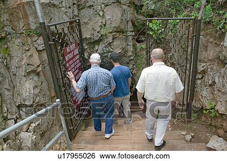 Stock Photograph - Tourists walking into cave. Fotosearch