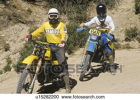 Stock Image - Two dirt bike riders on their off-road motorcycles. Fotosearch