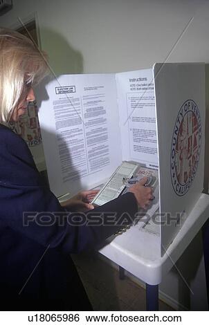 Woman voter in a voting booth selecting choices on a ballot View Large Photo Image Stock Photograph - Woman voter in a voting booth selecting choices on a ballot. Fotosearch