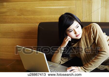 Close-up of a young woman lying on a couch in front of a laptop View Large Photo Image Stock Image - Close-up of a young woman lying on a couch in front of a laptop. Fotosearch
