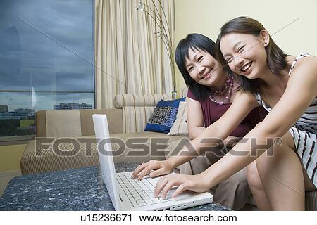 Portrait of a mature woman and her daughter using a laptop and smiling View Large Photo Image Stock Image - Portrait of a mature woman and her daughter using a laptop and smiling. Fotosearch