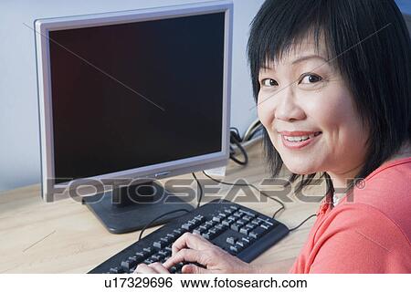 Portrait of a mature woman using a computer and smiling View Large Photo Image Stock Photograph - Portrait of a mature woman using a computer and smiling. Fotosearch