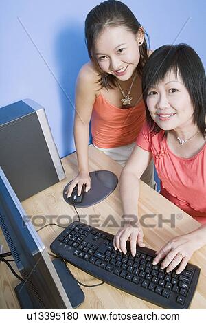 Portrait of a young woman and her mother using a computer and smiling View Large Photo Image Stock Image - Portrait of a young woman and her mother using a computer and smiling. Fotosearch