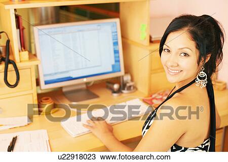 Portrait of a young woman smiling and using a computer View Large Photo Image Stock Image - Portrait of a young woman smiling and using a computer. Fotosearch