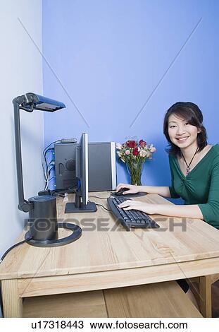 Stock Image - Portrait of a young woman using a computer and smiling. Fotosearch