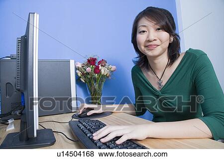 Portrait of a young woman using a computer and smirking View Large Photo Image Stock Photo - Portrait of a young woman using a computer and smirking. Fotosearch