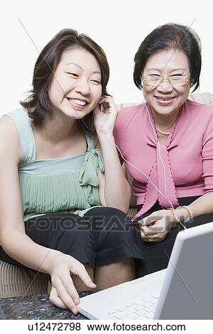 Senior woman and her granddaughter using a laptop and listening to music View Large Photo Image Stock Photo - Senior woman and her granddaughter using a laptop and listening to music. Fotosearch