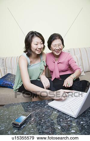 Senior woman and her granddaughter using a laptop and smiling View Large Photo Image Stock Photo - Senior woman and her granddaughter using a laptop and smiling. Fotosearch