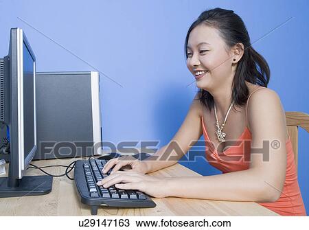 Side profile of a young woman using a computer and smiling View Large Photo Image Stock Image - Side profile of a young woman using a computer and smiling. Fotosearch
