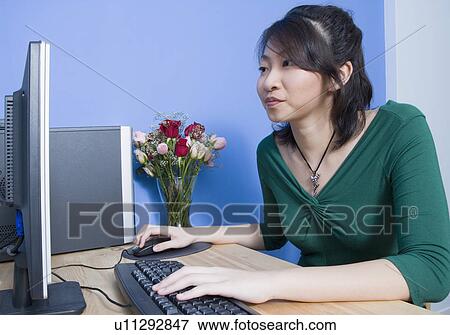 Side profile of a young woman using a computer View Large Photo Image Stock Photo - Side profile of a young woman using a computer. Fotosearch