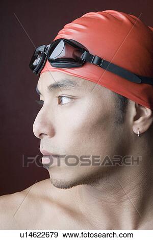 Stock Photo - Close-up of a young man wearing a swimming cap. Fotosearch