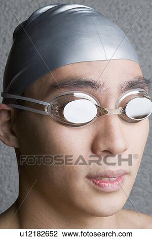 Stock Image - Close-up of a young man wearing swimming goggles. Fotosearch