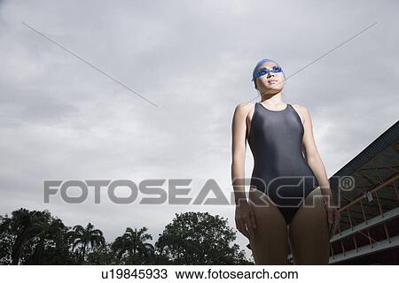 Low angle view of a young woman wearing swimwear View Large Photo Image Stock Image - Low angle view of a young woman wearing swimwear. Fotosearch