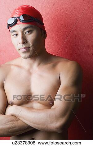 Stock Photo - Portrait of a young man standing with his arms crossed. Fotosearch