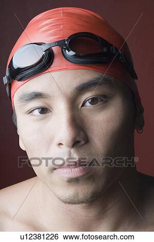 Stock Photograph - Portrait of a young man wearing a swimming cap. Fotosearch