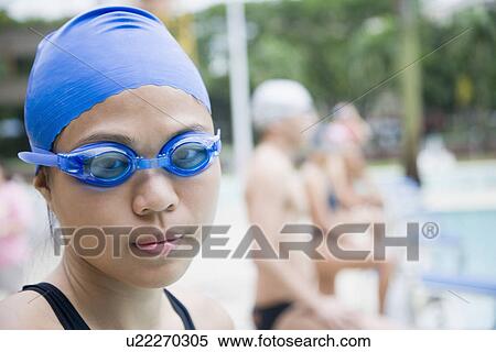 Portrait of a young woman wearing swimming goggles and standing at a poolside View Large Photo Image Stock Photography - Portrait of a young woman wearing swimming goggles and standing at a poolside. Fotosearch