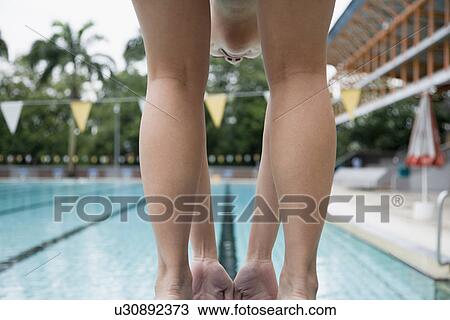 Stock Image - Rear view of a young man bending on a starting block. Fotosearch