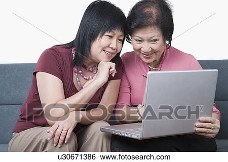 Close-up of a mature woman and a senior woman using a laptop and smiling View Large Photo Image Stock Photograph - Close-up of a mature woman and a senior woman using a laptop and smiling. Fotosearch