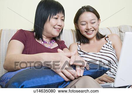 Close-up of a mature woman and her daughter using a laptop and smiling View Large Photo Image Stock Image - Close-up of a mature woman and her daughter using a laptop and smiling. Fotosearch