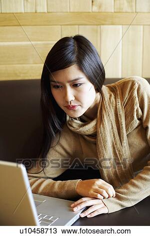 Stock Image - Close-up of a young woman looking at a laptop. Fotosearch