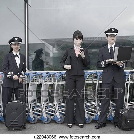 Female cabin crew standing with two pilots at an airport View Large Photo Image Stock Photograph - Female cabin crew standing with two pilots at an airport. Fotosearch