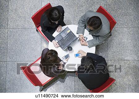 Picture - High angle view of two businesswomen with two businessmen in a conference room. Fotosearch
