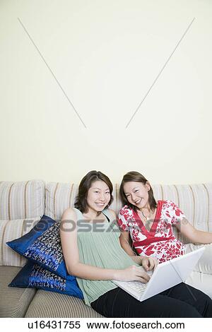 High angle view of two young women smiling and using a laptop View Large Photo Image Stock Photography - High angle view of two young women smiling and using a laptop. Fotosearch