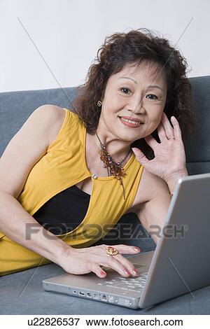 Stock Photo - Portrait of a senior woman using a laptop and smiling. Fotosearch
