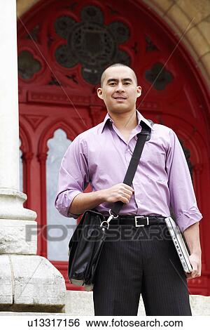 Stock Photograph - Portrait of a young man holding a laptop. Fotosearch