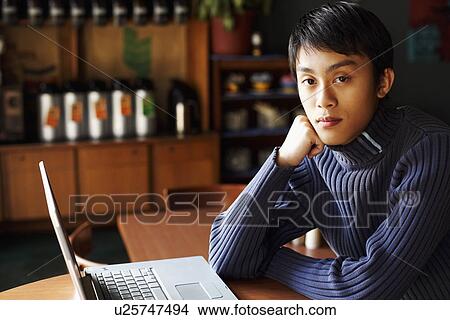 Picture - Portrait of a young man sitting in front of a laptop. Fotosearch