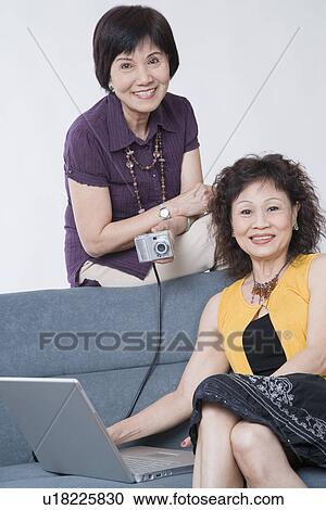 Portrait of two senior women sitting with a digital camera connected to a laptop View Large Photo Image Stock Image - Portrait of two senior women sitting with a digital camera connected to a laptop. Fotosearch