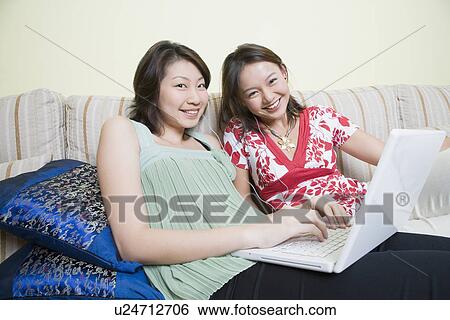 Portrait of two young women smiling and using a laptop View Large Photo Image Stock Photograph - Portrait of two young women smiling and using a laptop. Fotosearch