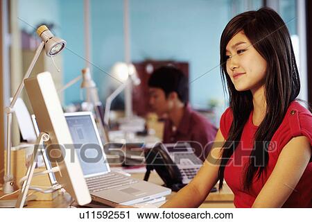 Side profile of a businesswoman sitting in front of a computer in an office View Large Photo Image Stock Image - Side profile of a businesswoman sitting in front of a computer in an office. Fotosearch