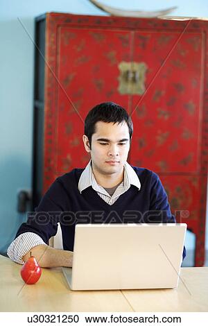 Young man using a laptop View Large Photo Image Stock Image - Young man using a laptop. Fotosearch