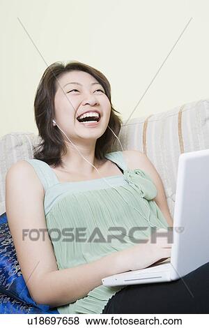 Stock Photo - Young woman using a laptop and laughing. Fotosearch