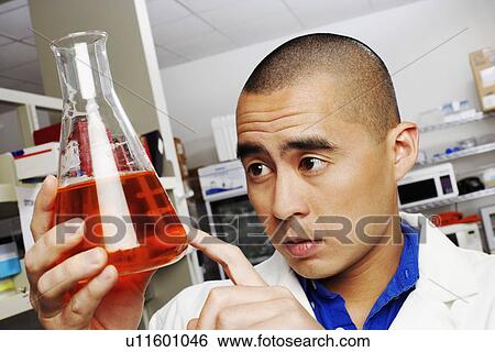 Close-up of a male pharmacist looking at a conical flask View Large Photo Image Stock Photograph - Close-up of a male pharmacist looking at a conical flask. Fotosearch