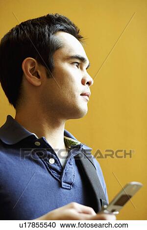 Close-up of a young man holding a mobile phone View Large Photo Image Stock Image - Close-up of a young man holding a mobile phone. Fotosearch