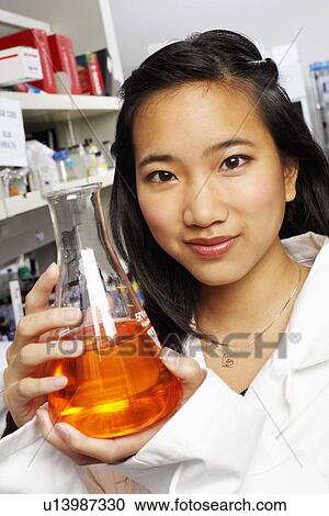 Stock Image - Portrait of a female pharmacist holding a conical flask in a laboratory. Fotosearch
