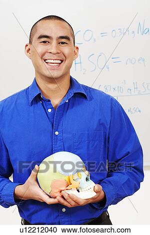 Stock Image - Portrait of a professor holding a skull in the classroom and smiling. Fotosearch