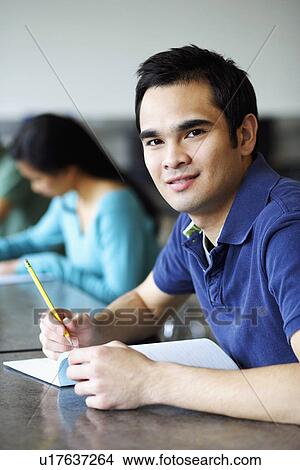 Picture - Portrait of a young man giving exams in a classroom and grinning. Fotosearch