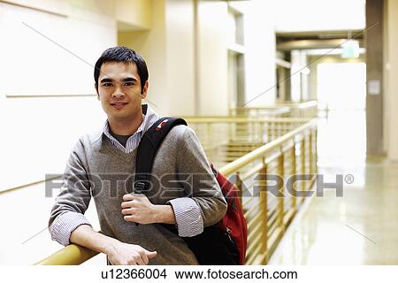 Picture - Portrait of a young man leaning against the railing of a corridor. Fotosearch